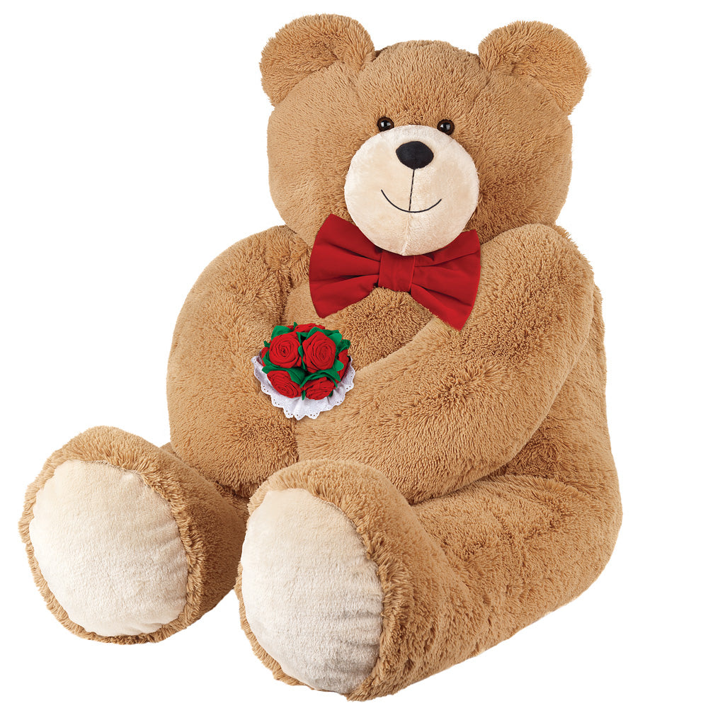 Large light brown teddy bear with a red bow tie holding a bouquet of red roses.