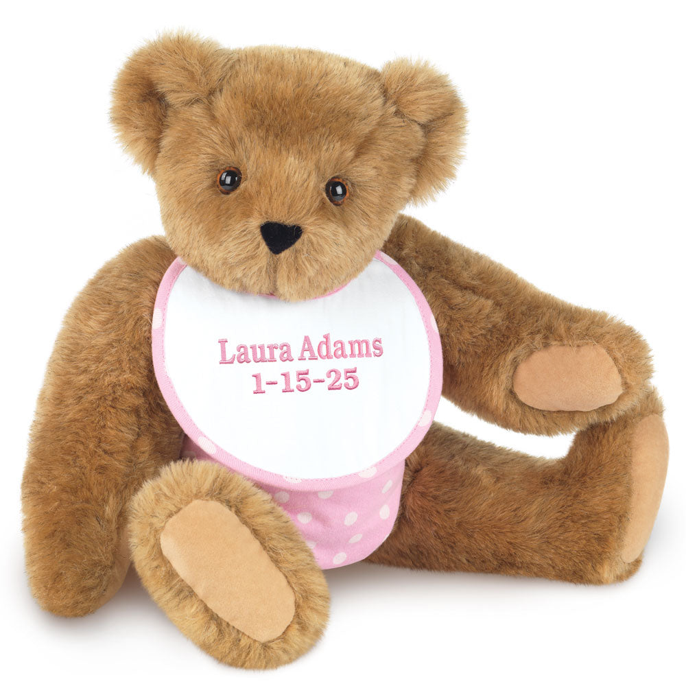 Honey brown plush baby bear with black eyes and embroidered white bib with pink text and polka dots.