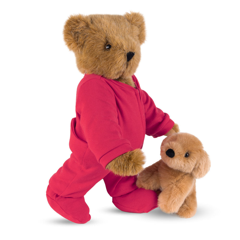 Honey-colored teddy bear wearing red pajamas holding a small tan plush puppy.