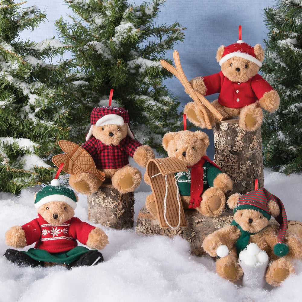 Set of five vintage-style teddy bear holiday ornaments dressed in festive winter clothes, posed on snow with pine trees.