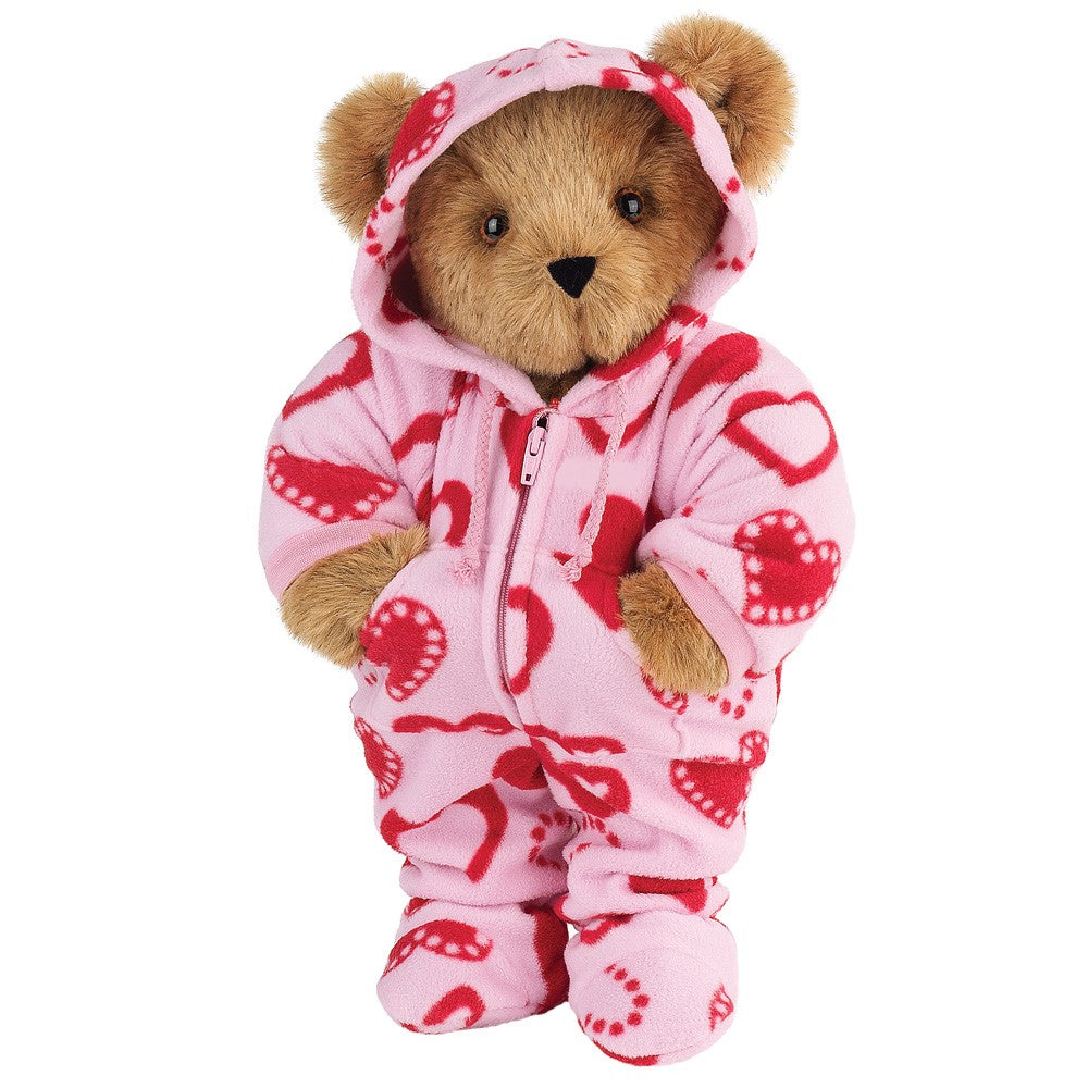 Brown plush teddy bear wearing pink hoodie-footie with red and white heart patterns and zipper front.