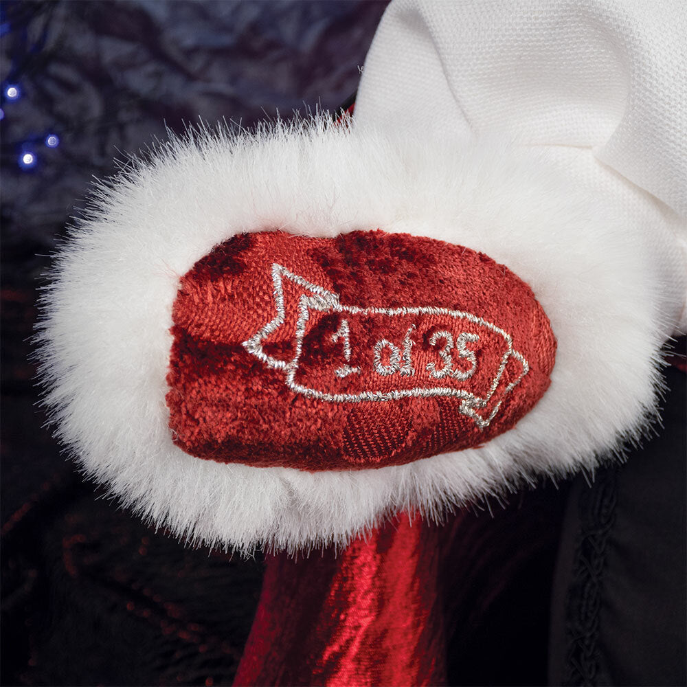 White plush paw with ornate red fabric patch embroidered with "1 of 35" on red velvet background.
