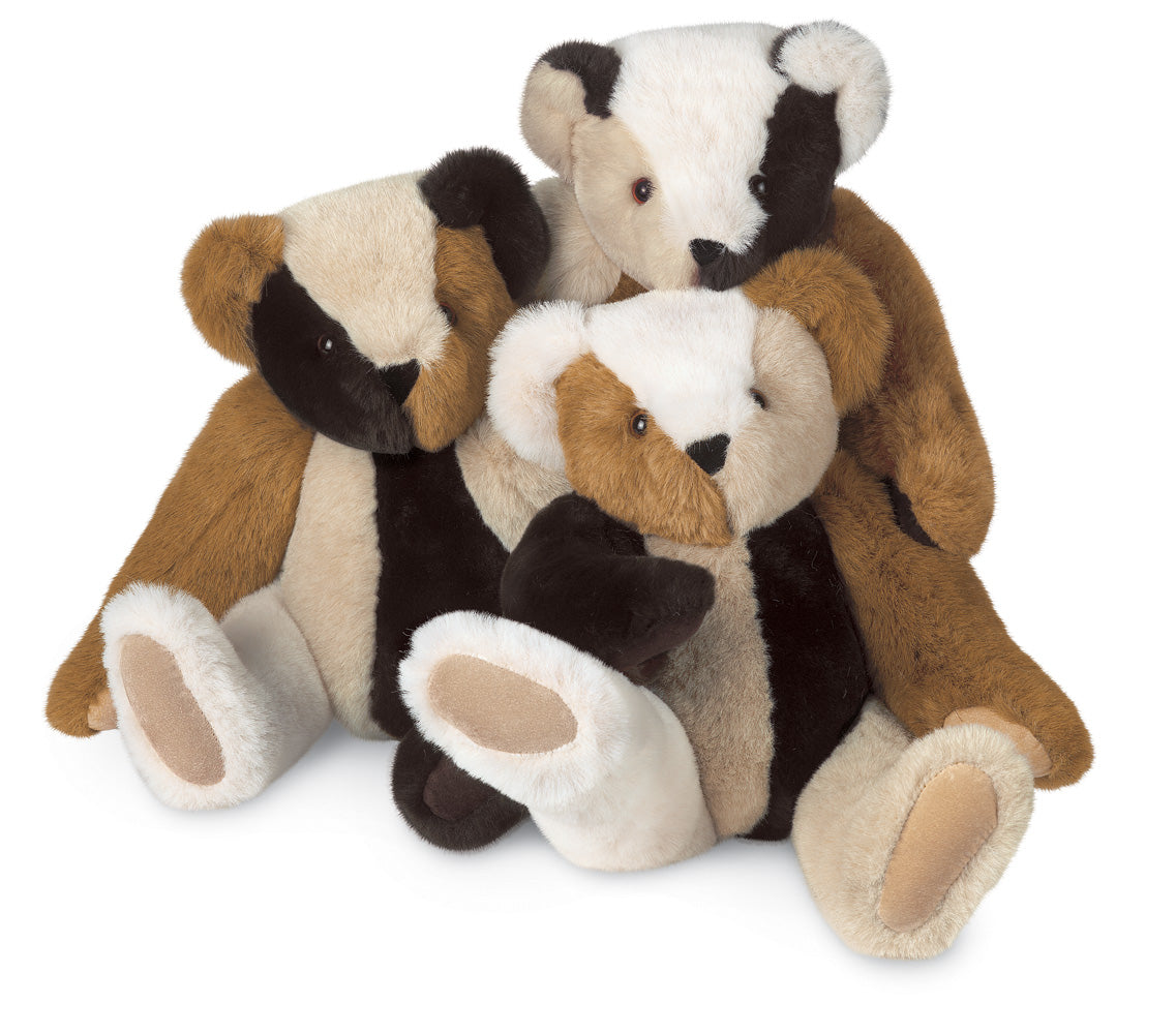 Soft patchwork teddy bear with brown, black, and white fur sitting with arms around a smaller bear.