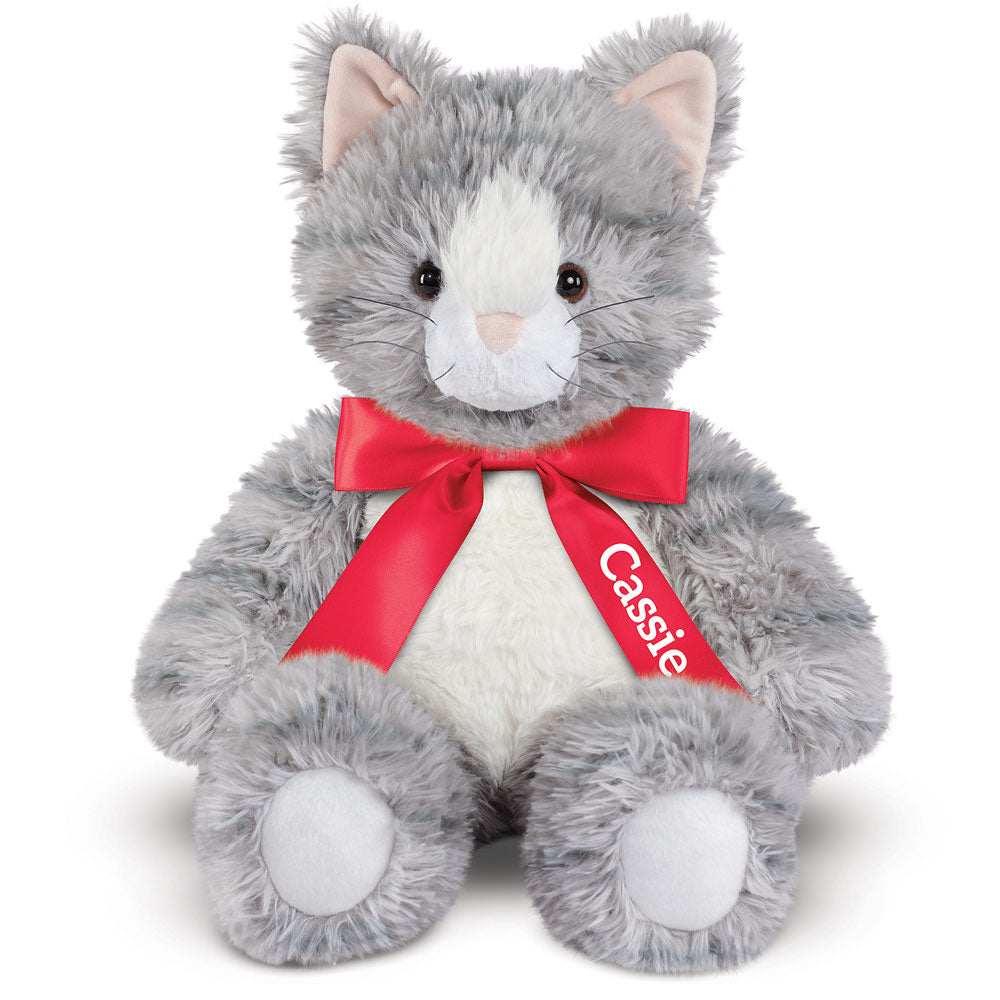 Gray and white plush kitten with pink ears and red ribbon bow labeled Cassie.