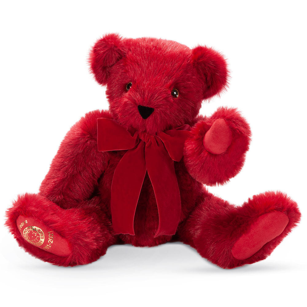 Plush deep red teddy bear with matching velvet bow and embroidered gold 40th anniversary emblem on paw.