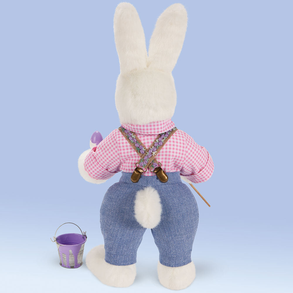White plush Easter Bunny wearing pink gingham shirt and blue pants with suspenders, holding purple flower and small purple.