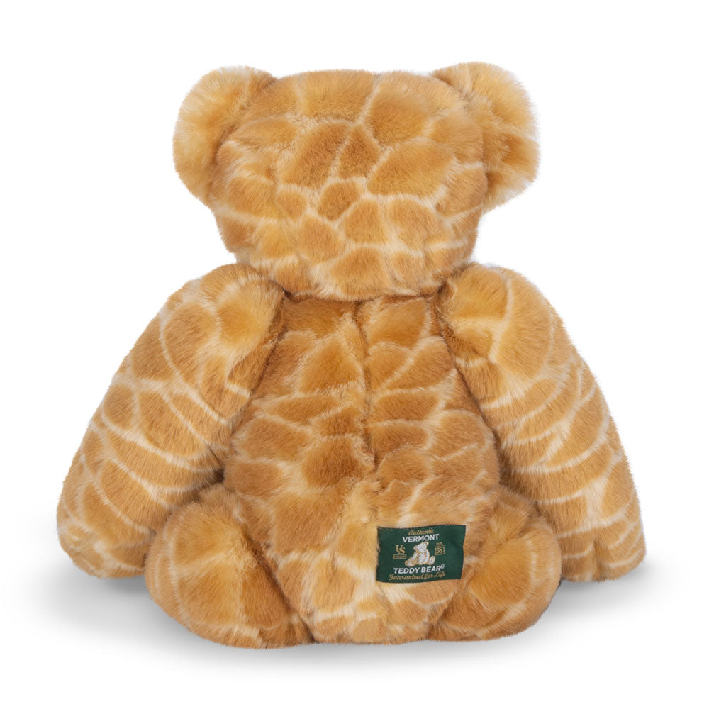 Plush bear with giraffe-patterned fur and green embroidered patch on back.