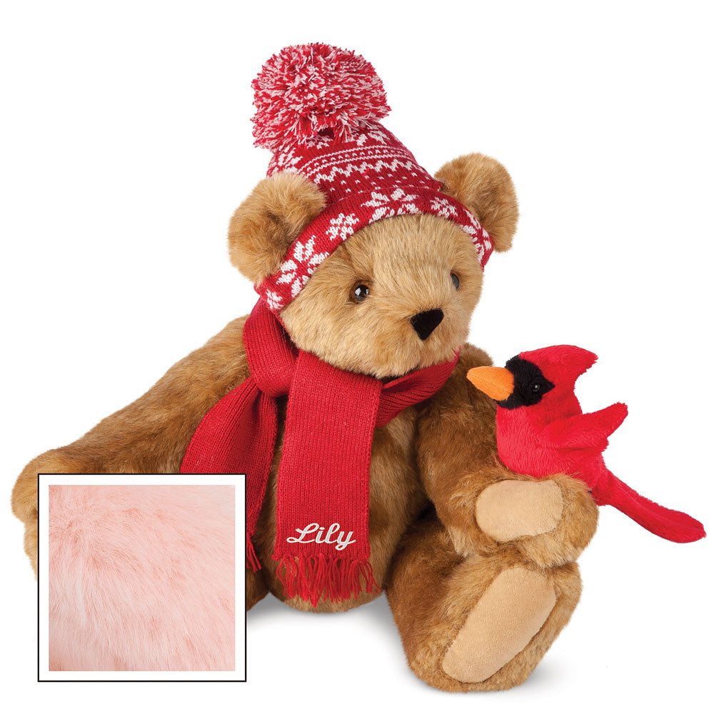 Honey brown plush bear wearing a red knit hat and scarf holding a red cardinal plush bird.