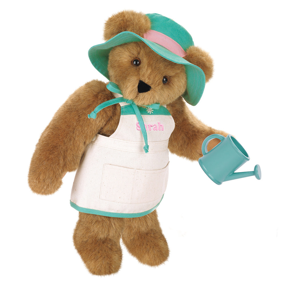 Brown plush bear wearing a green sunhat and white apron holding a small blue watering can.