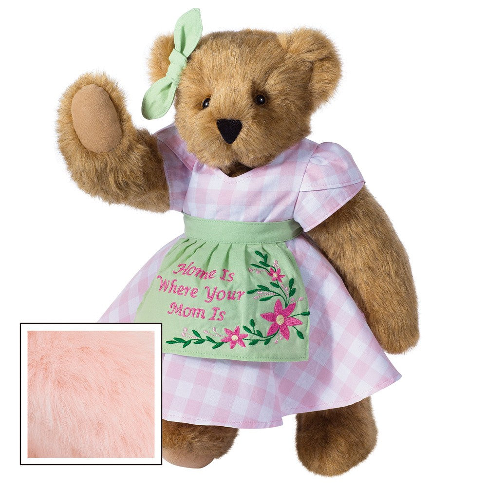 Honey-colored teddy bear wearing pink gingham dress with green embroidered apron and matching bow.