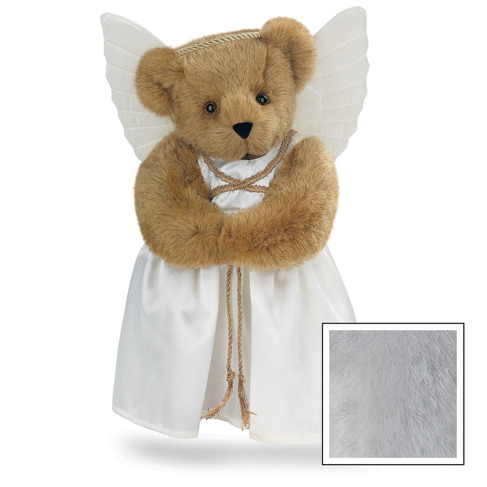Honey-colored teddy bear with brown eyes wearing white angel wings and a white gown tied with gold cord.