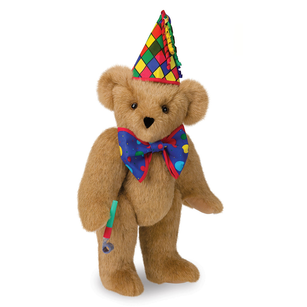 Tan plush bear wearing a multicolored diamond-patterned party hat and a blue bow tie with red and yellow accents, holding a.