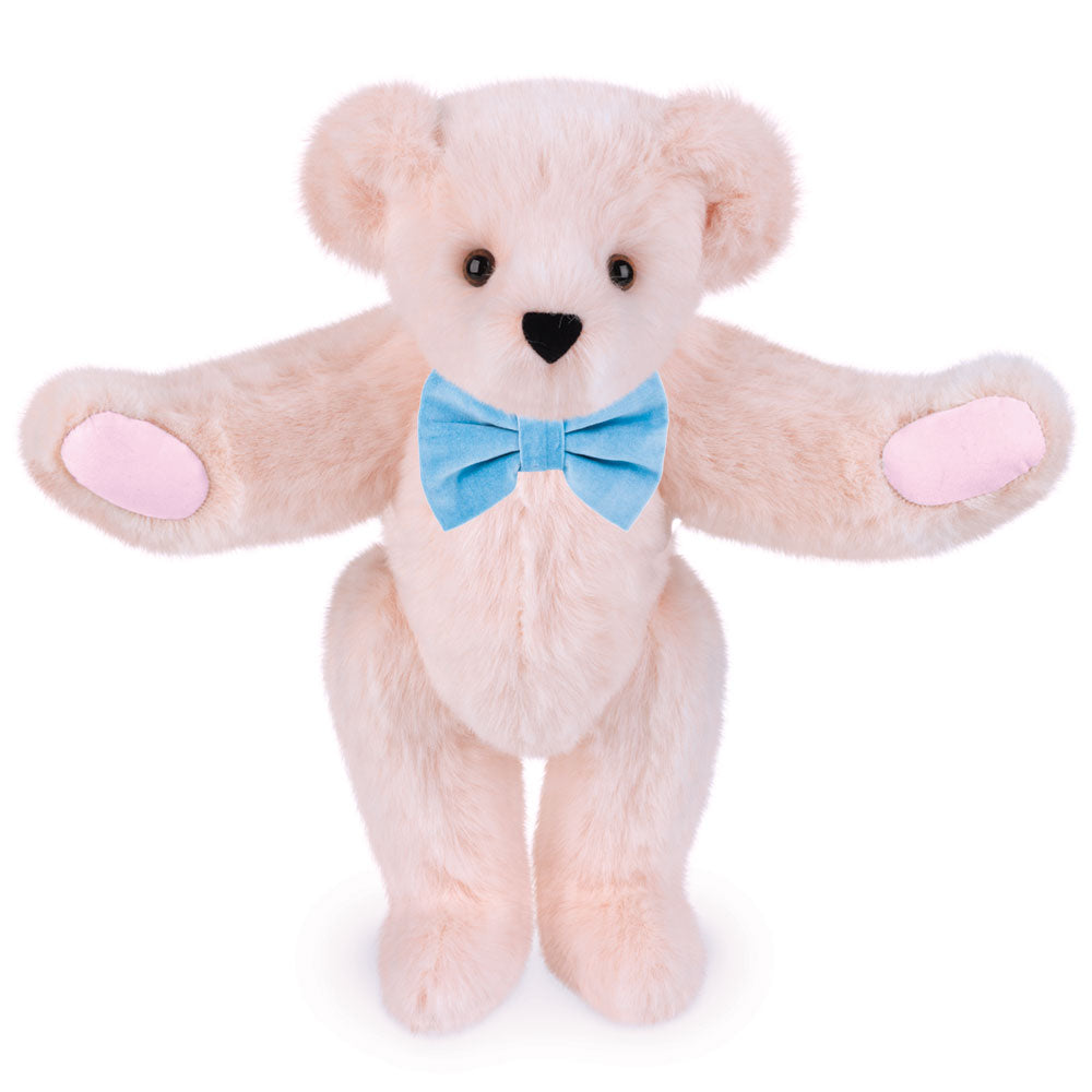 Light pink plush bear with brown eyes and a light blue bow tie, soft fabric.