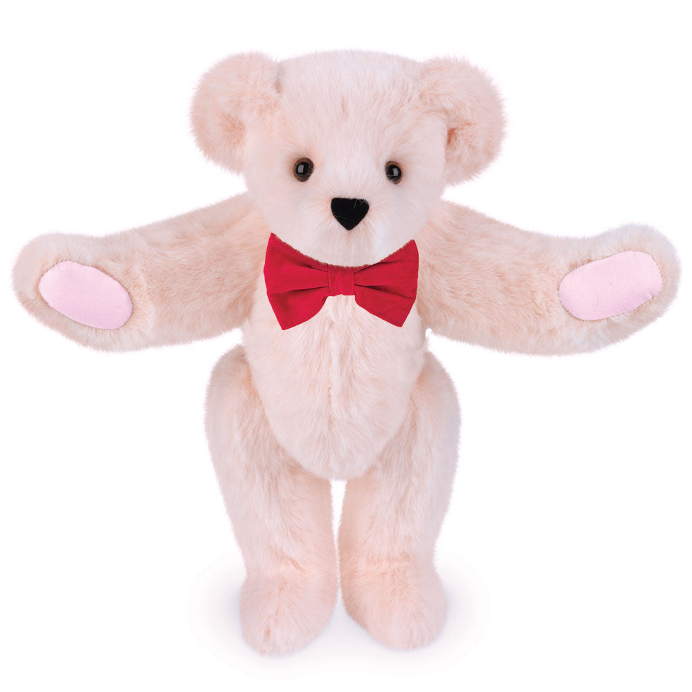 Soft bubblegum pink plush bear with brown eyes, light pink paw pads, and a red bow tie.