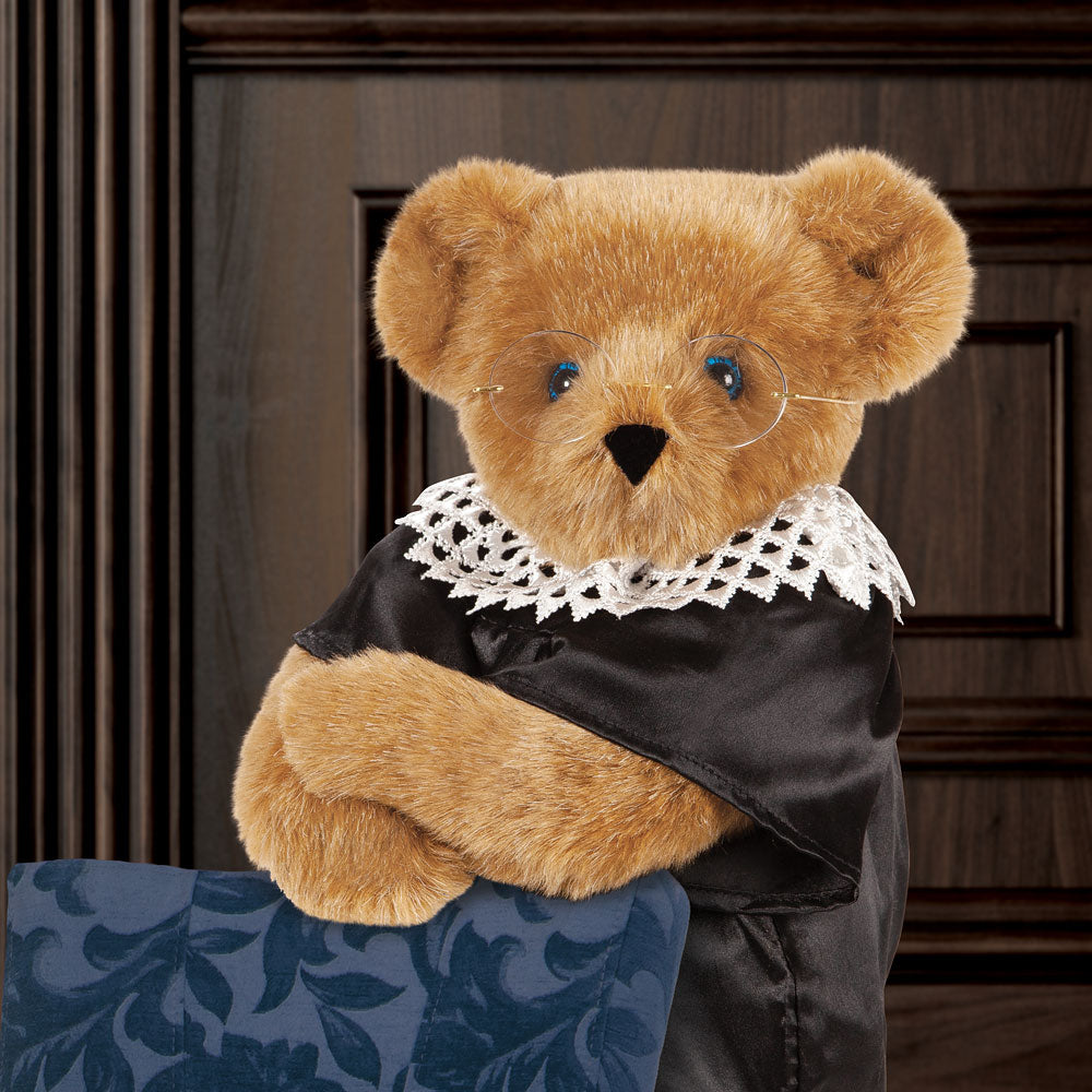 15-inch brown plush bear wearing black robe and white lace collar sitting on blue patterned chair.
