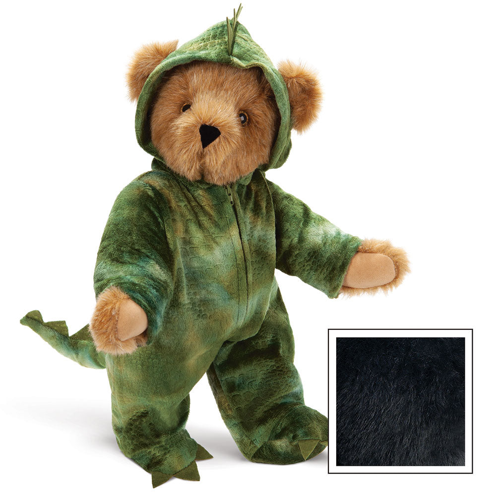 Brown teddy bear wearing a green dinosaur costume with tail and hood on white background.
