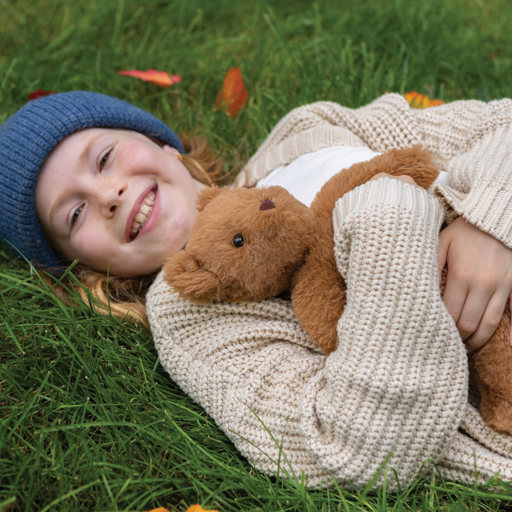 Child hugging 15" Buddy Teddy Bear on a lawn in autumn.
