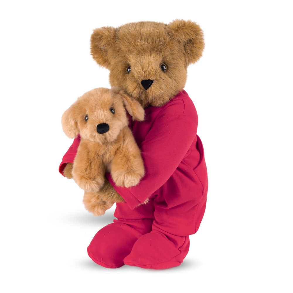 Honey-colored teddy bear wearing red pajamas holding a small light brown puppy plush with black nose.
