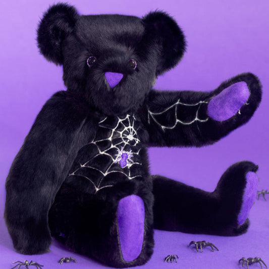 Black Halloween teddy bear with purple accents on a purple background with purple spiders and glow in the dark web. Great Halloween Decor.