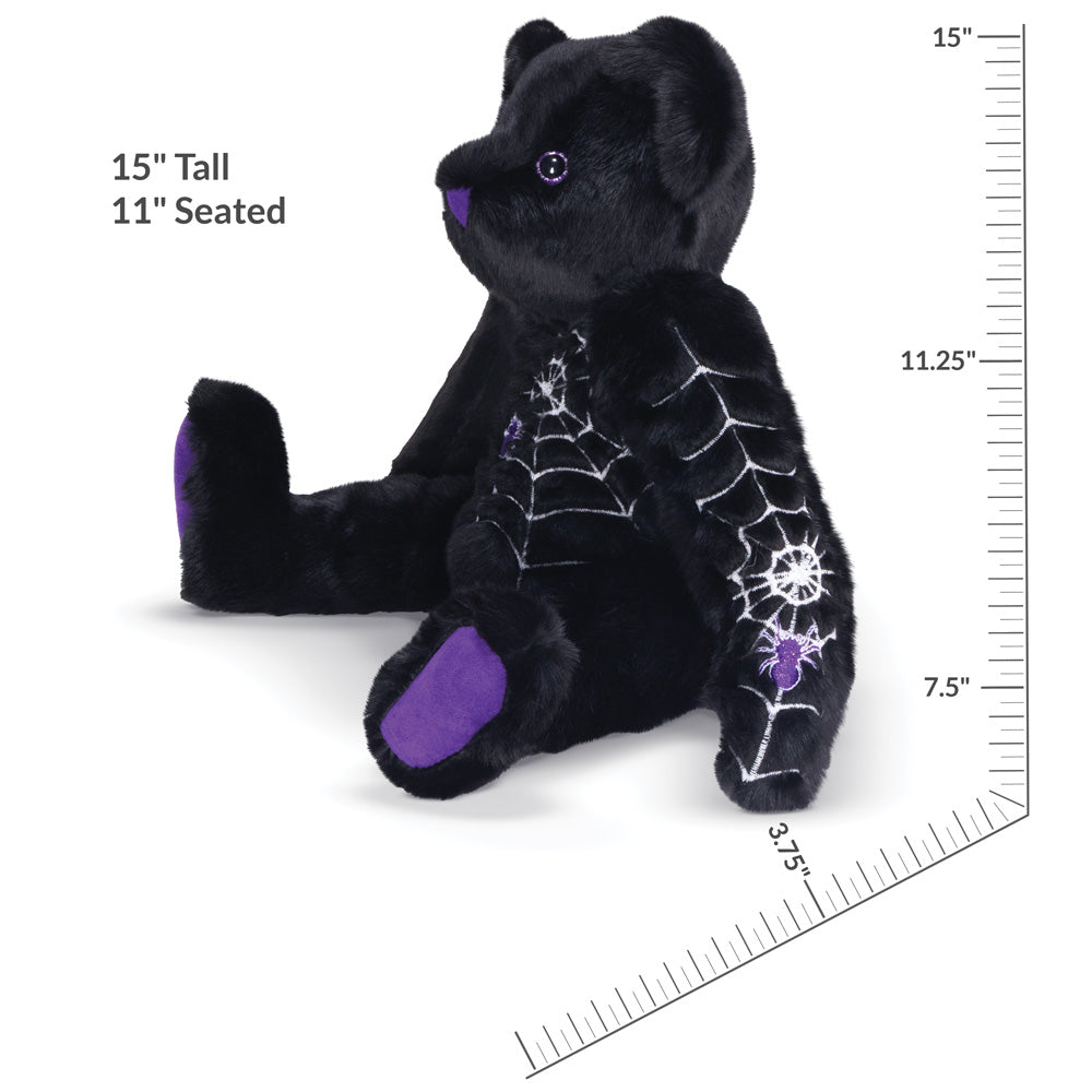 Side view of sitting black teddy bear with spider web and spider design with measurements of 15" tall and 11" seated.