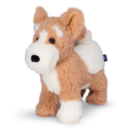 A plush dog toy with tan and white fur, standing on a white background. The toy has a small blue tag on its back.