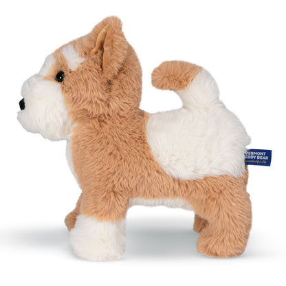 Side view of a plush dog stuffed animal in tan and white faux fur. A blue fabric tag on the side reads 'VERMONT TEDDY BEAR'.