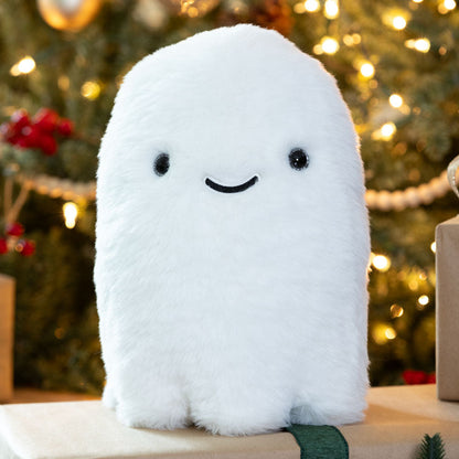 White plush ghost toy with black eyes and a smile on a Christmas tree background
