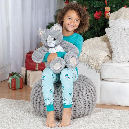 Child holding a plush toy in front of a Christmas tree with presents.