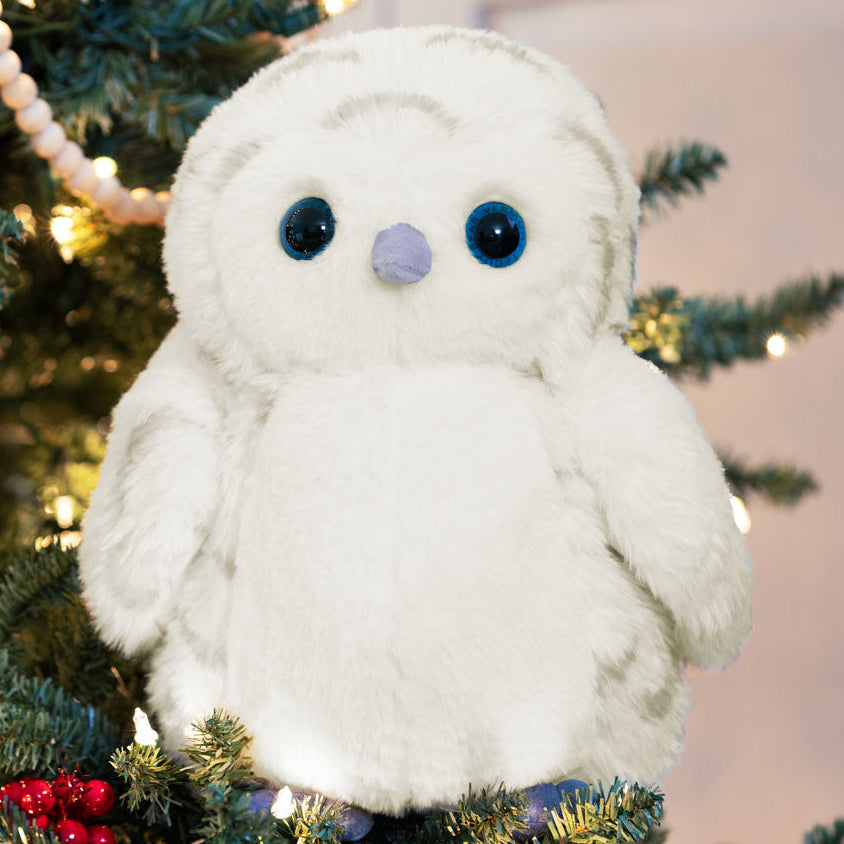 Owl plush owl toy in front of a decorated Christmas tree