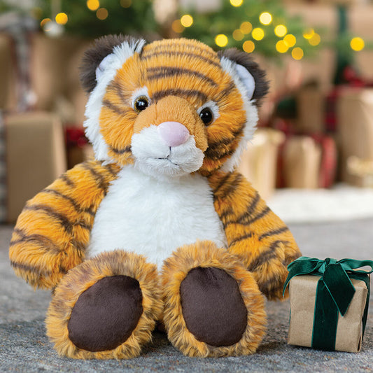 Plush tiger toy with a gift box in front of a decorated Christmas tree.