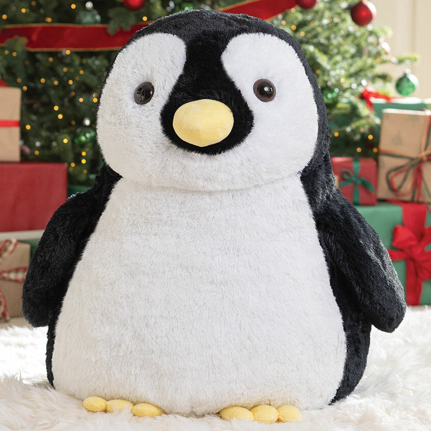 Plush penguin toy in front of Christmas gifts and tree