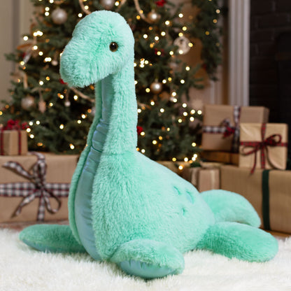 Plush dinosaur toy in front of a decorated Christmas tree with presents.