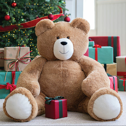Large teddy bear in front of a Christmas tree with holiday gifts