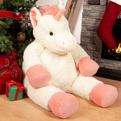 Plush unicorn toy in front of a Christmas tree with presents and stockings.