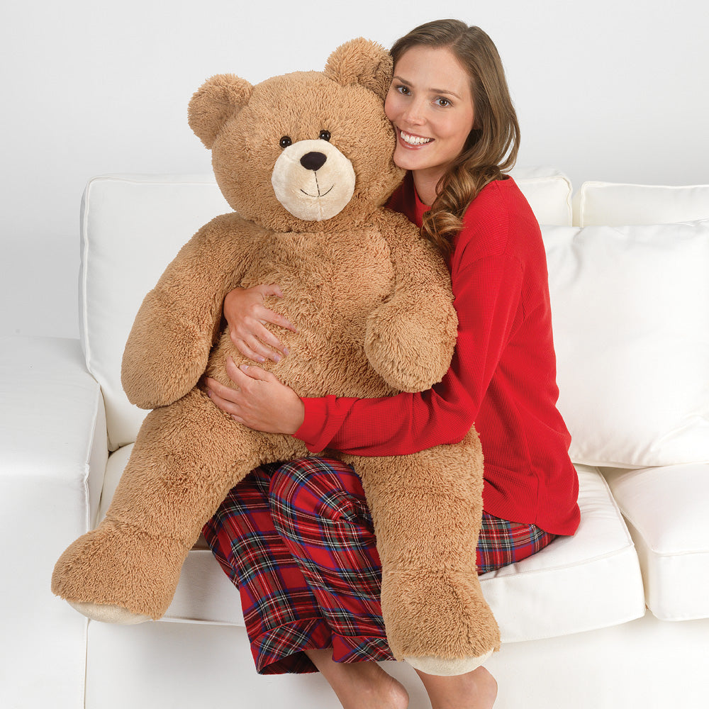 Woman holding a large teddy bear on a white couch