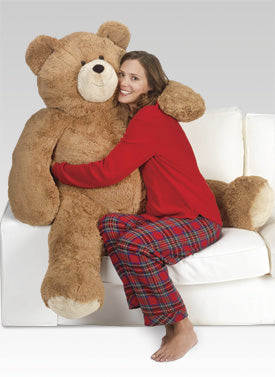 Woman in red pajamas hugging a giant teddy bear on a white couch