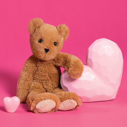 Brown teddy bear with pink hearts on a pink background