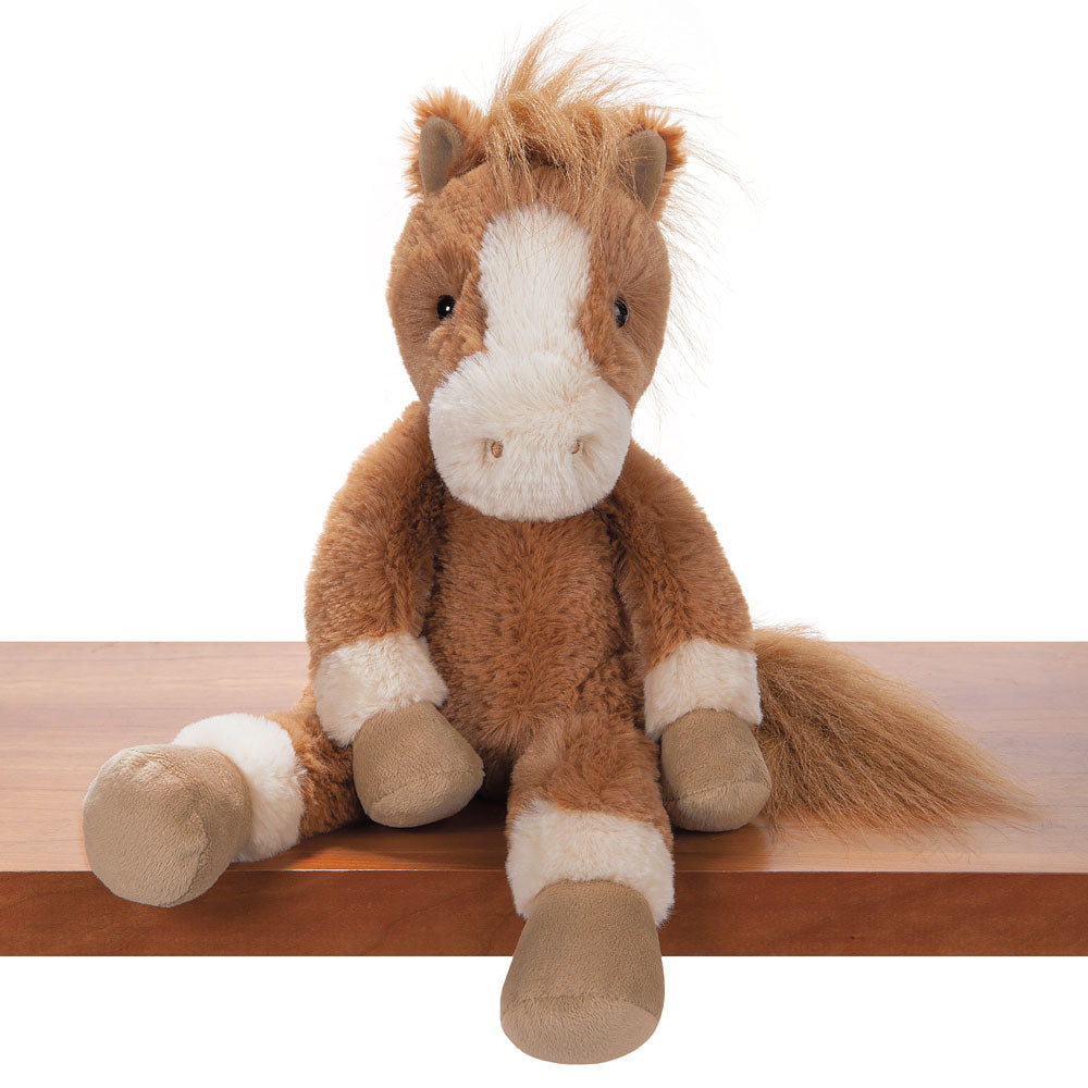 Brown and white plush pony with soft fur and a fluffy tail sitting on a wooden surface.
