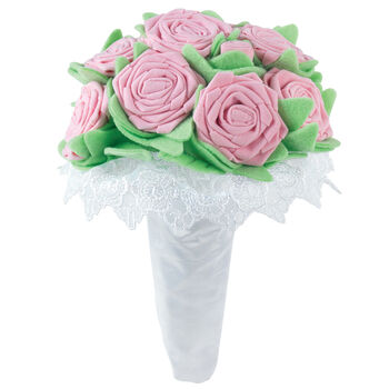 Large bouquet of soft pink felt roses with green leaves and white lace trim wrapped in white fabric.