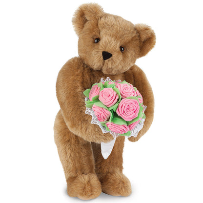 Brown teddy bear holding a bouquet of pink rose-shaped foam flowers with white lace accents.