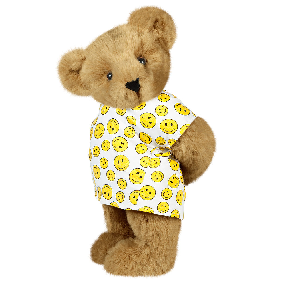 Honey-colored teddy bear wearing a white shirt with yellow smiley faces and brown eyes.